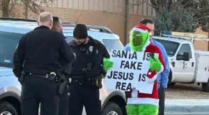 Parents Implode after Grinch Stands outside School Holding Up a Sign